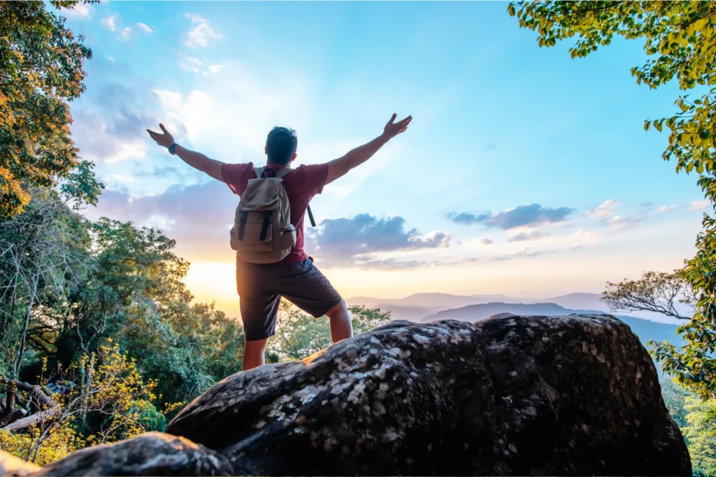 rear-view-portrait-young-man-traveler-with-backpack-standing-mountain-with-arms-spread